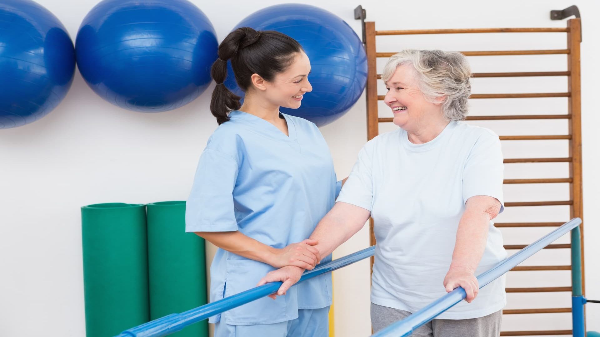 Therapeutin begleitet eine Patientin beim Üben am Gehbarren